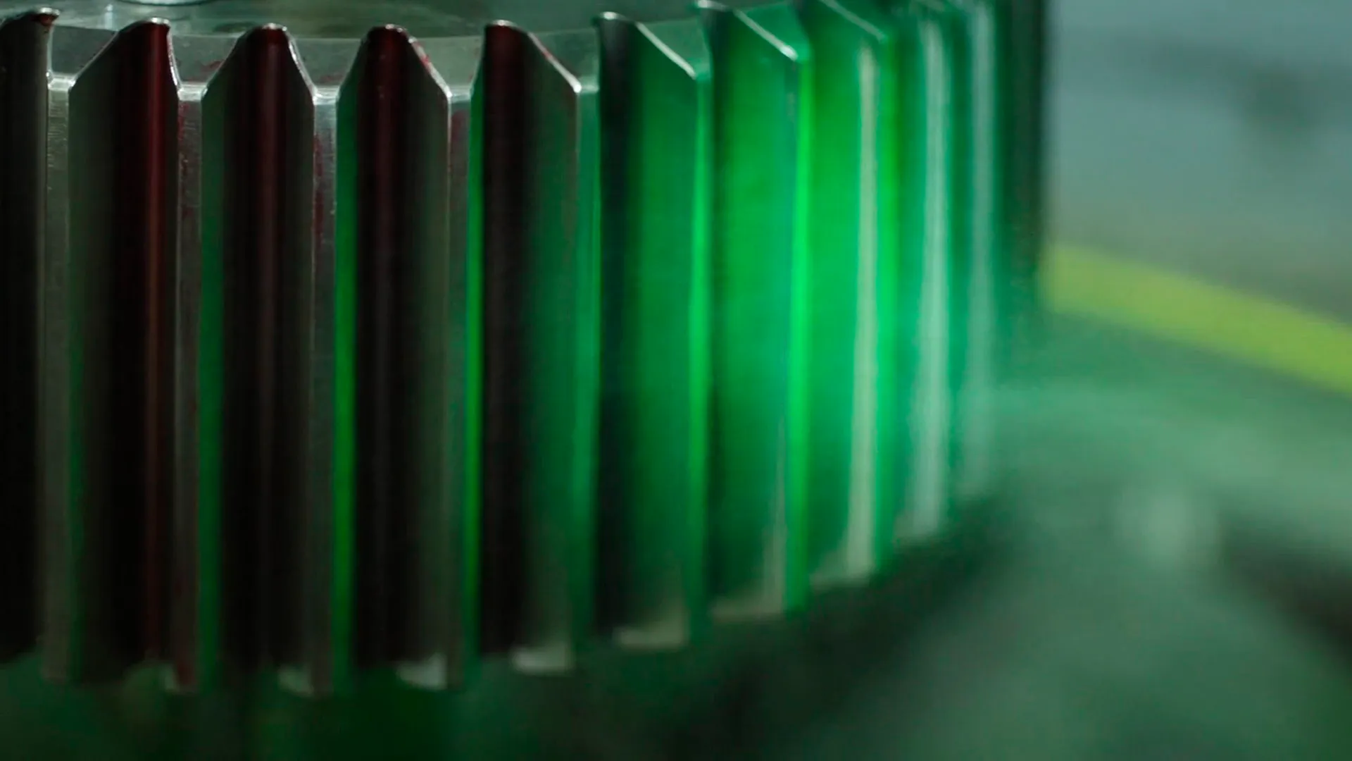 Nahaufnahme einer metallischen Verzahnung im grünen Licht aus dem Industriefilm für RENK.